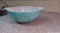 Single turquoise Pyrex Amish Butterprint Cinderella bowl with white interior, shown from top angle.