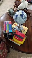View of entire lot on round wooden table, including View-Master, disks, globe, Munsch book, and Harry Potter books