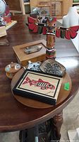 Wood art collection including totem pole, framed art, lazy Susan, small dish, and wooden box on table
