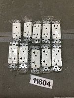 Set of 10 snow white decorator style tamper-resistant wall outlets individually wrapped, showing front face of outlets with standard three-prong configuration