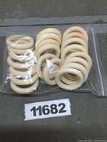 Clear plastic bag filled with 21 uniform natural wood rings stacked inside, all rings circular and unpainted.