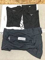 Three t-shirts laid flat on a surface, two black and one dark gray, showing their size and condition.