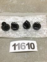 Four black aluminum tripod mount adapters arranged on bubble wrap, front view showing the mounting slots.