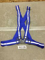 Full view of blue safety vest with reflective stripes laid flat showing the X-back style and adjustable straps.