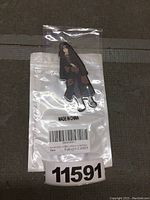 Front view of the anime pendant sealed in plastic packaging showing the character details and packaging label.