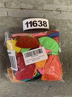 Photo of a sealed plastic bag containing multiple colorful latex balloons with labels visible showing product code and country of manufacture.