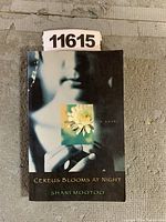 Front cover of 'Cereus Blooms at Night' by Shani Mootoo showing a person holding a flower picture with title and author text.