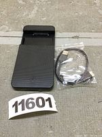 Black external enclosure case with sliding top, designed to house 2.5 inch SATA HDD/SSD. USB cable sealed in plastic bag beside it.