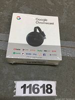 Front view of sealed Google Chromecast box showing device image and supported streaming services logos.