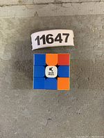Top view of a stickerless GAN Swift Block 355S 3x3 speed cube with blue, orange, and white sides visible showing the cube's design and central Swift Block logo.