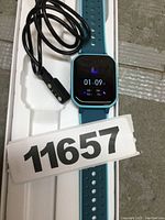 Close-up of watch display showing time and sleep monitoring data with charging cable attached.