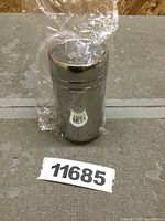 Front view of sealed stainless steel powder shaker with mesh lid on a concrete surface.