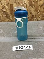 Blue Rubbermaid bottle with white flip lid, side view showing loop handle