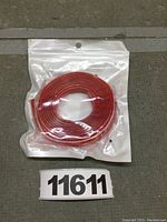 Photo of a coiled red furniture edge protector strip in sealed transparent plastic pouch.