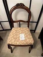 Front view of antique wooden chair with carved grapes and leaves and upholstered seat