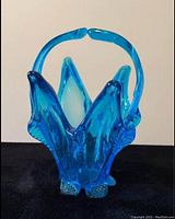Front view of the handmade blue glass basket showing its petal-shaped design and handle.