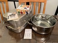 Overview of roasting pan, stainless steel cooking pot with glass lid, and two sets of cookie cutters on table with lot number 118