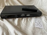Front view of Panasonic DVD Player/DVD Recorder with Philips remote on top, showing Panasonic logo and device model area.