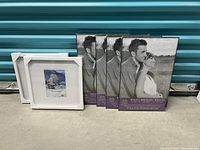 Lot displaying six picture frames standing upright, four black and two white frames.