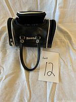 Front view of small black leather Roots purse showing dual side zippered compartments and one handle