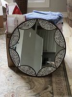 Full view of the round mirror showing the entire item including its mosaic frame and reflective glass center.