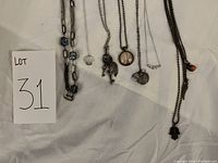 Photo showing all 7 necklaces laid on white background with lot number card visible