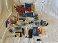 Full overview of the complete office supply lot including pens, staples, pushpins, paper clips, measuring tape, markers, and digital timer.