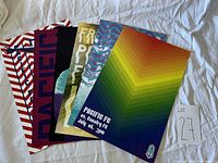 Photo showing six various Pacific FC game day posters laid out in a fan shape showing differing graphic designs and colors.