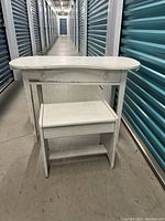 Solid wood kidney-shaped desk/vanity table with matching stool in a storage unit hallway.