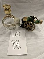 Two vintage mini liquor bottles: a Courvoisier bottle displayed on a miniature cannon stand and a round Chambord bottle with a crown cap, photographed with a LOT 88 sign.