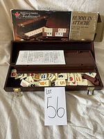 Open wooden attache case with Rummy tiles spilling out inside, original box visible in background