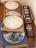 Four large decorative plates and a set of five bowls in original boxes, plus chopsticks on a tray.