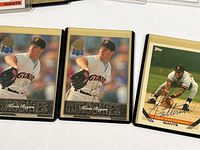 Close-up of three baseball cards including two Kevin Rogers cards and one John Patterson signed card, all in plastic sleeves.