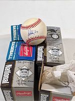 Photo showing one autographed official National League baseball by Salomon Torres with its box, along with other baseball boxes marked with player names and dates.