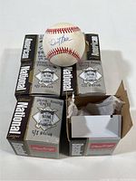 Photo showing Dusty Baker autographed baseball on top of Rawlings National League boxes labeled with player names and location S/J Arena.