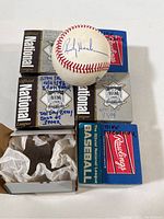 Baseball signed by Rickey Henderson with its box in the background featuring player names and inscriptions