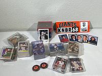 Array of unsorted baseball cards in plastic boxes, KNBR 68 Giants bumper stickers and KRON 4 news trading cards