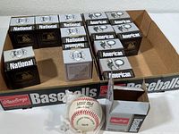 Wide shot of 13 Rawlings baseball boxes and some unboxed balls in cardboard tray.