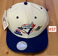 Front view of the white and blue baseball cap with embroidered 1992 Blue Jays logo, World Champions text, and World Series patch, showing original MLB tag attached.
