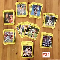 Photo shows assorted stacks of yellow-bordered baseball trading cards featuring various 1991 MLB players laid out on a wooden surface.