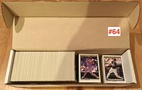 Image showing a large quantity of 1991 O-Pee-Chee Premiere baseball cards packed in a cardboard box. Two cards are shown at side, featuring players in batter poses.