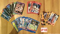 Photo showing grouping of baseball cards in various colors and designs laid out on wooden floor.