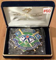 Front view of the limited edition pin in its original blue velvet box lined with white satin featuring gold printed text.