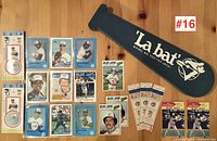 Photo showing baseball cards, three ticket stubs, and a La Bat foam bat laid out on a wooden surface.