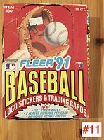Photo of the original red Fleer 1991 baseball cards box with large baseball glove image and text emphasizing logo stickers and trading cards, 36 count, showing price sticker and some wear.