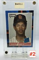 Clear image of Roberto Alomar rookie baseball card enclosed in a protective case with label 'Rookie' on top. Card depicts the player image and card details.