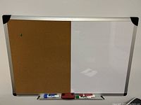 Combination board half cork bulletin, half white dry erase with markers and eraser on bottom tray.