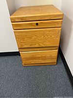 Image of a 2-drawer wooden filing cabinet with light oak finish and lock on upper drawer.
