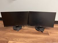 Photo of two Asus VA229 monitors side-by-side on wooden surface with attached HDMI cables.