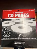 Red and white box packaging of Vaultz CD Pages 50-pack showing brand, capacity, and storage details